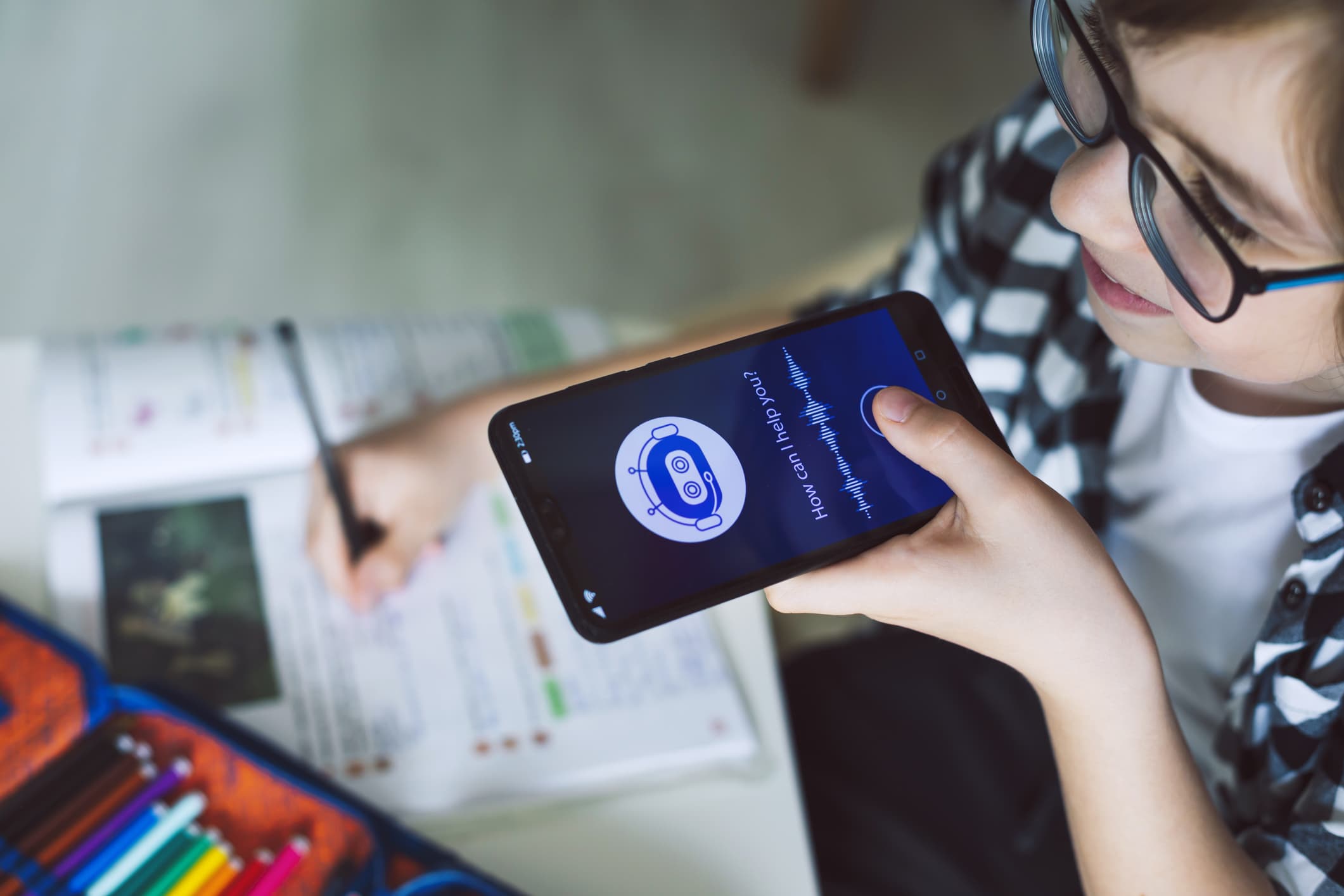 Smiling boy using system AI Chatbot on mobile application. Chatbot conversation, Ai Artificial Intelligence technology. Futuristic technology. Virtual assistant on internet.