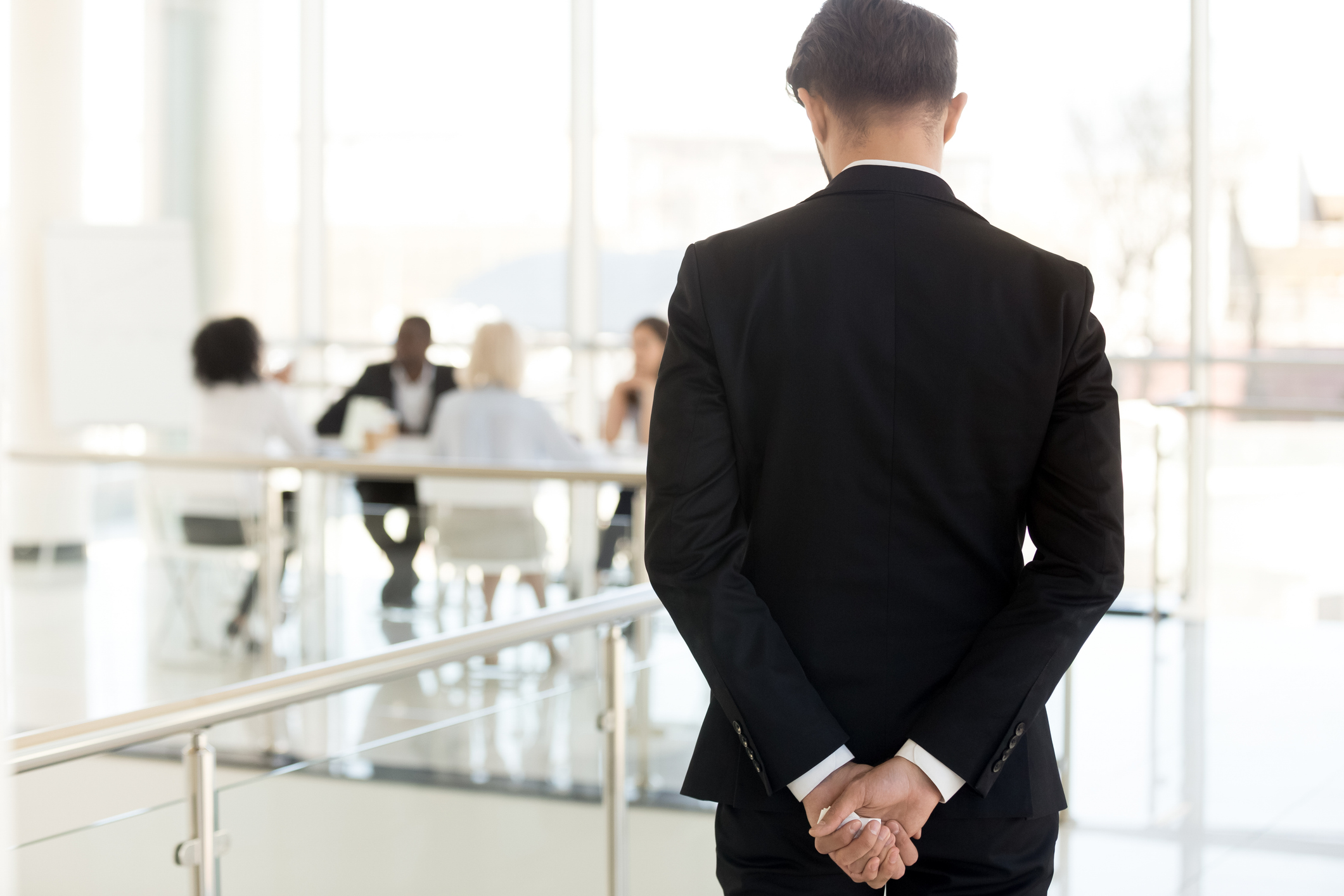 Nervous businessman waiting to enter at business meeting rear view