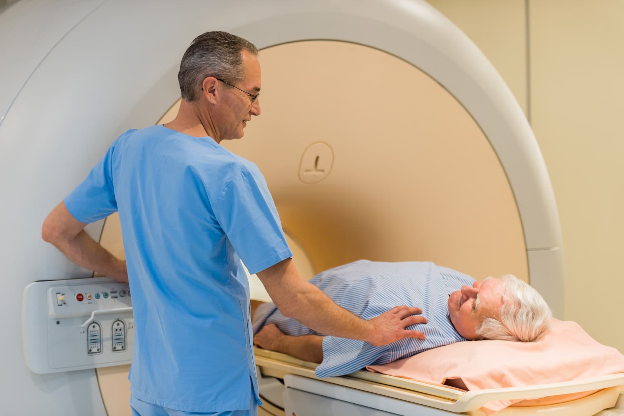 Radiologist consoling a senior patient at MRI scan.